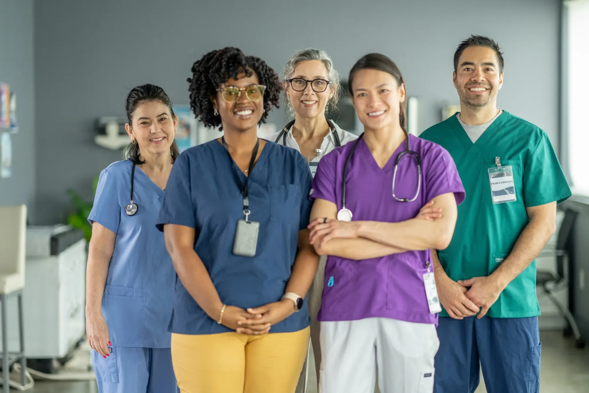 A diverse group of five healthcare clinicians standing together